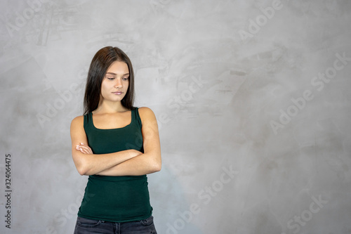 Young pretty woman with sad disappointed face cross hands on grey background. copy space.