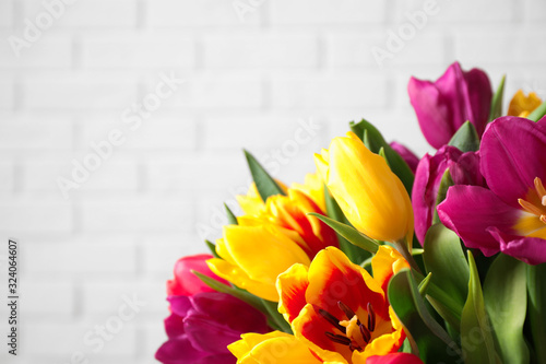 Beautiful spring tulips against white brick wall  closeup. Space for text