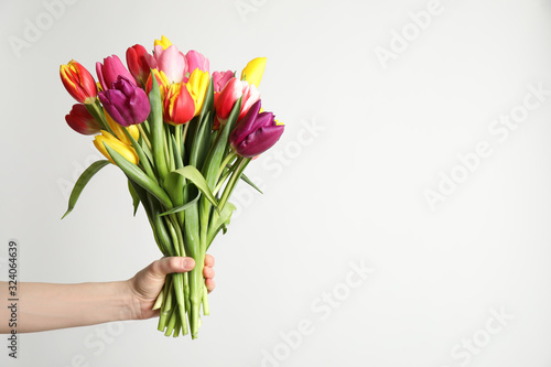 Woman holding beautiful spring tulips on white background, closeup. Space for text photo