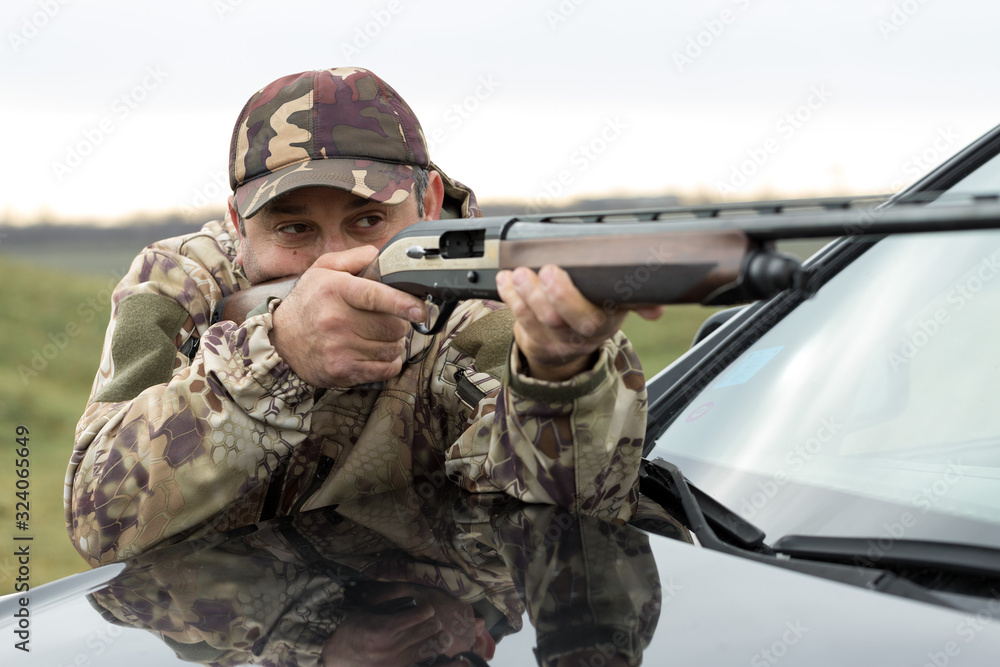 A hunter in camouflage at the shooting range calibrates the weapon. A man shoots at targets.