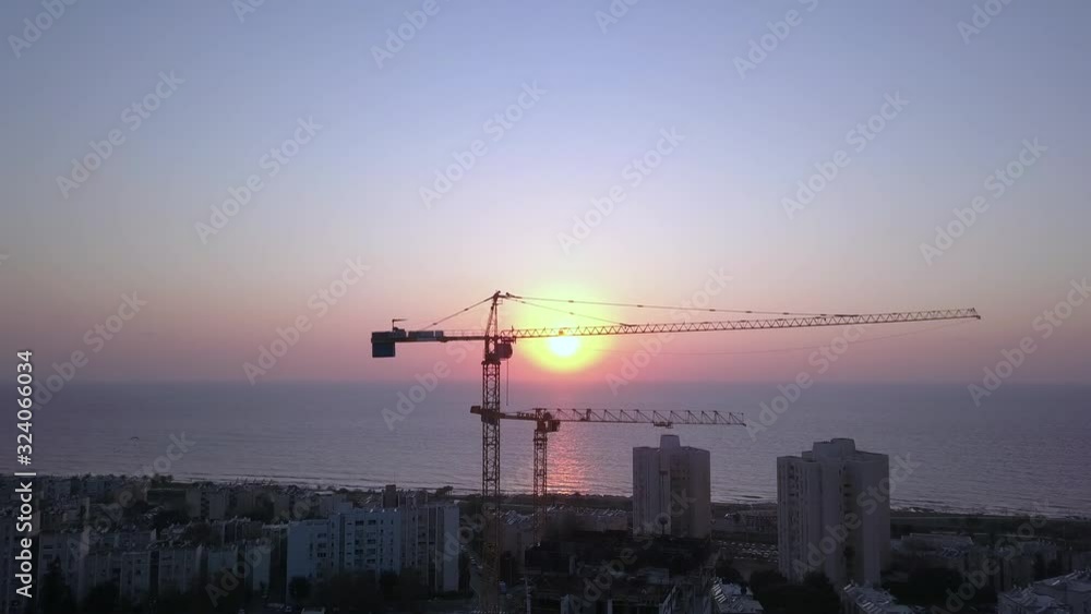 Silhouette of a crane in action at a construction site and stunning sunset in the background. Silhouette of a crane in action at a construction site and stunning sunset in the background.