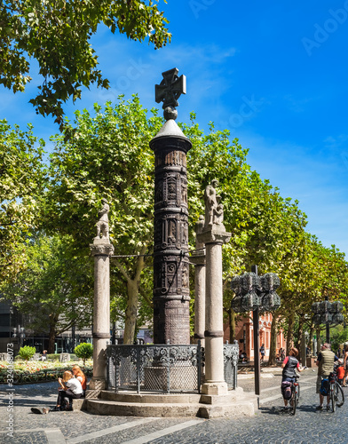 People walking and enjoying view of Nagelsaule Monument, located near Mainz Cathedral, in Old Town of Mainz, Germany