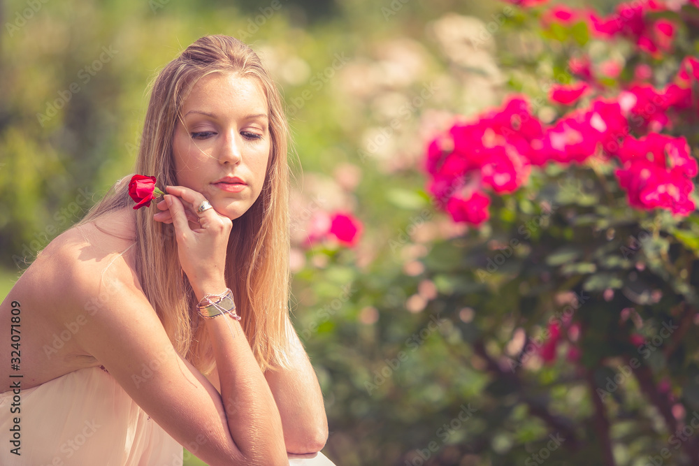 Young beautiful blonde woman in blooming garden. Concept fashion woman relaxing in the garden. Young beautiful blonde woman in blooming garden. Concept fashion woman relaxing in the garden.