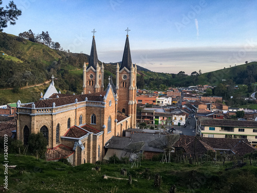 Typical Antioquia Village with Big Catedral Surrounded of Green Hills of Pastures and Mountains Aerial View in Belmira, Antioquia / Colombia photo