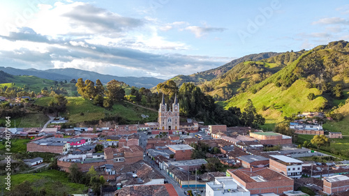 Typical Antioquia Village with Big Catedral Surrounded of Green Hills of Pastures and Mountains Aerial View in Belmira, Antioquia / Colombia photo