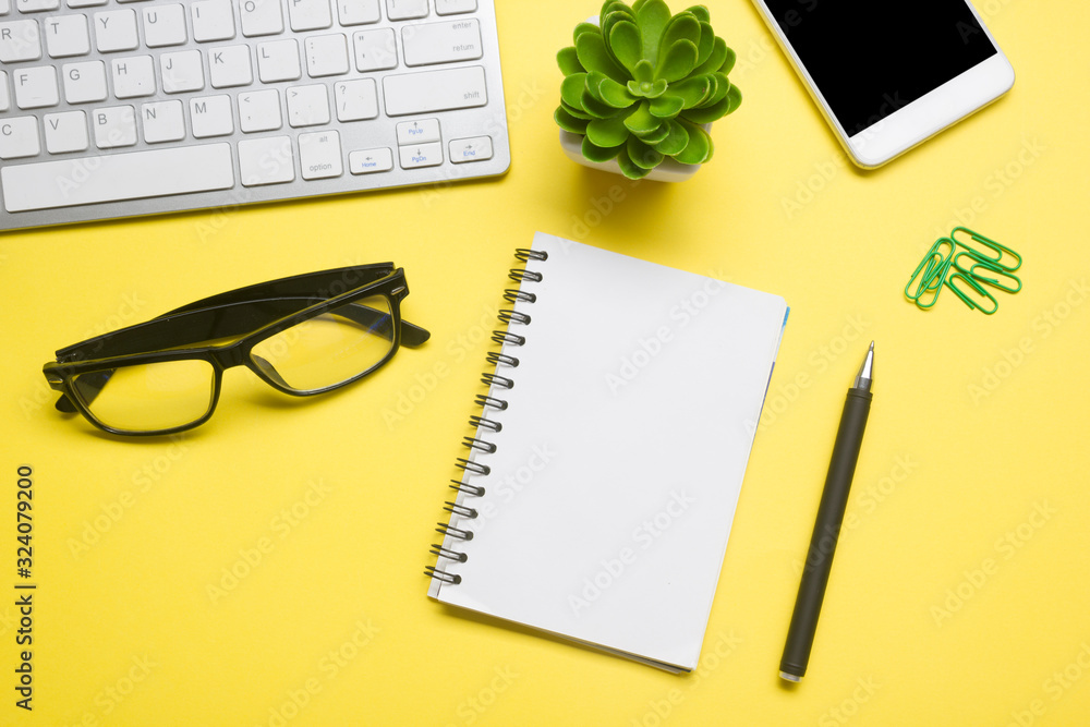 Yellow desk office with laptop, smartphone and other work supplies with cup of coffee. Top view with copy space for input the text. Designer workspace on desk table essential elements on flat lay Yellow desk office with laptop, smartphone and other work supplies with cup of coffee. Top view with copy space for input the text. Designer workspace on desk table essential elements on flat lay