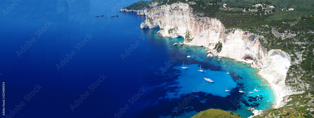 Aerial drone ultra wide photo of breathtaking turquoise exotic bay of blue lagoon in island of Paxos visited by sail boats, Ionian, Greece