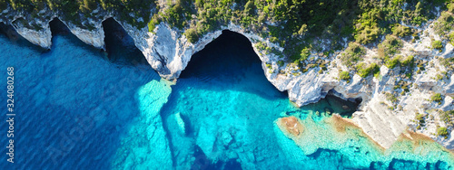 Aerial drone ultra wide photo of tropical white rocky bay of blue lagoon with turquoise clear waters, white volcanic caves and sail boats docked, island of Paxos, Ionian, Greece photo