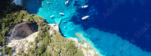 Aerial drone ultra wide photo of tropical white rocky bay of blue lagoon with turquoise clear waters, white volcanic caves and sail boats docked, island of Paxos, Ionian, Greece