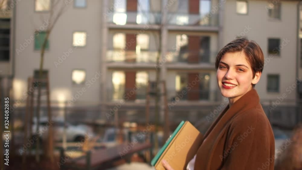 Portrait of a young girl in the courtyard of a multi-storey building. New building and real estate, housewarming. Short-haired girl with red lipstick Portrait of a young girl in the courtyard of a multi-storey building. New building and real estate, housewarming. Short-haired girl with red lipstick