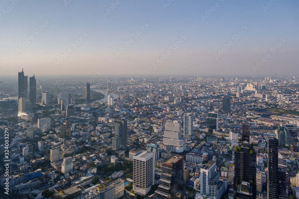 Aerial view of skyline and cityscape of Bangkok, urban buildings along Chao Phraya river, with background of twilight sky before sunset with air pollution of pm 2.5 dust, from Mahanakorn Building.