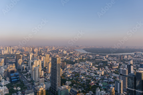 Aerial view of skyline and cityscape of Bangkok, urban buildings along Chao Phraya river, with background of twilight sky before sunset with air pollution of pm 2.5 dust, from Mahanakorn Building. © Peeradontax