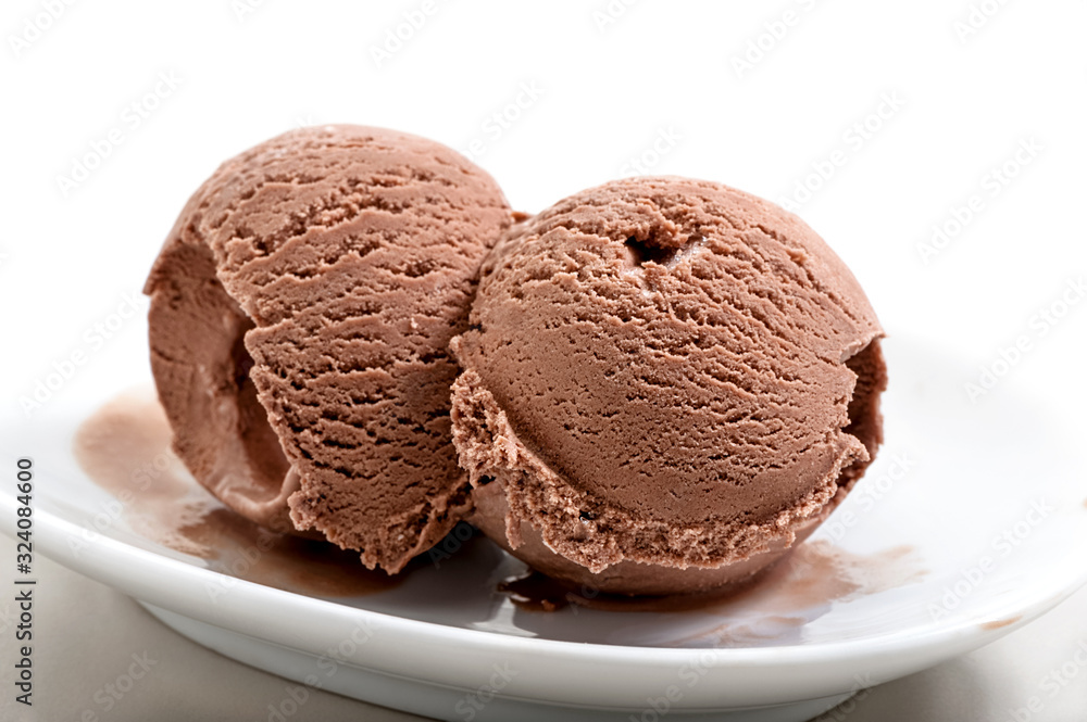 two frozen balls of chocolate ice cream on porcelain saucer close-up against white background two frozen balls of chocolate ice cream on porcelain saucer close-up against white background