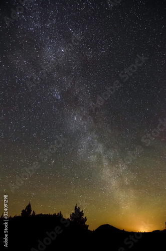 USA, California, Modoc County, Lava Beds National Monument. Milky Way Galaxy stretches into the night sky above the glow from Klamath Falls, OR.