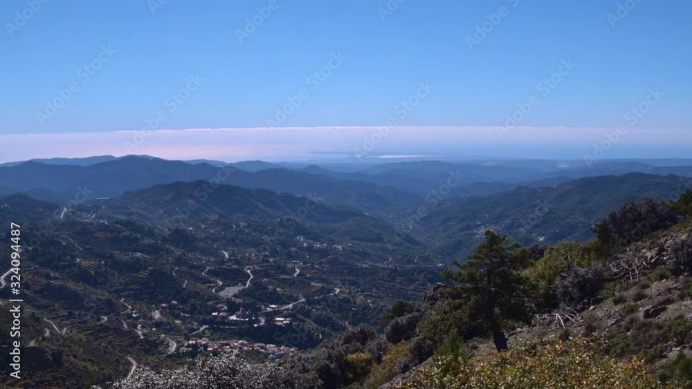 Aerial drone view over the mountain peak revealing villages in the distance Aerial drone view over the mountain peak revealing villages in the distance