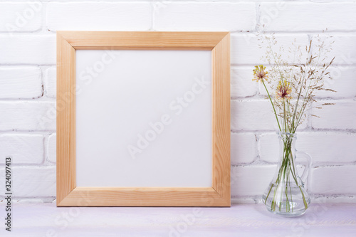 Wooden square frame mockup with grass in the glass jug