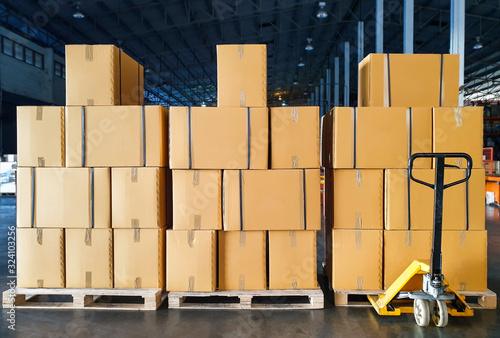 Stack of package boxes on wooden pallets and hand pallet truck in storage warehouse. Supply chain Shipping warehouse delivery shipment goods, Cargo and logistics
