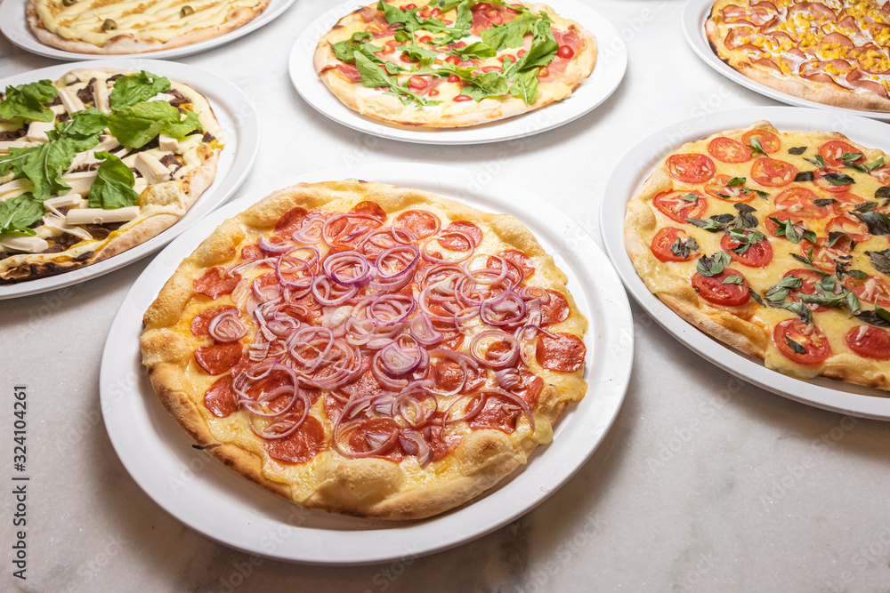 Various pizzas on the white marble table Various pizzas on the white marble table