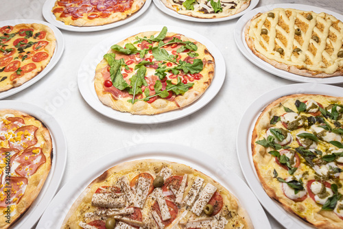 Various pizzas on the white marble table