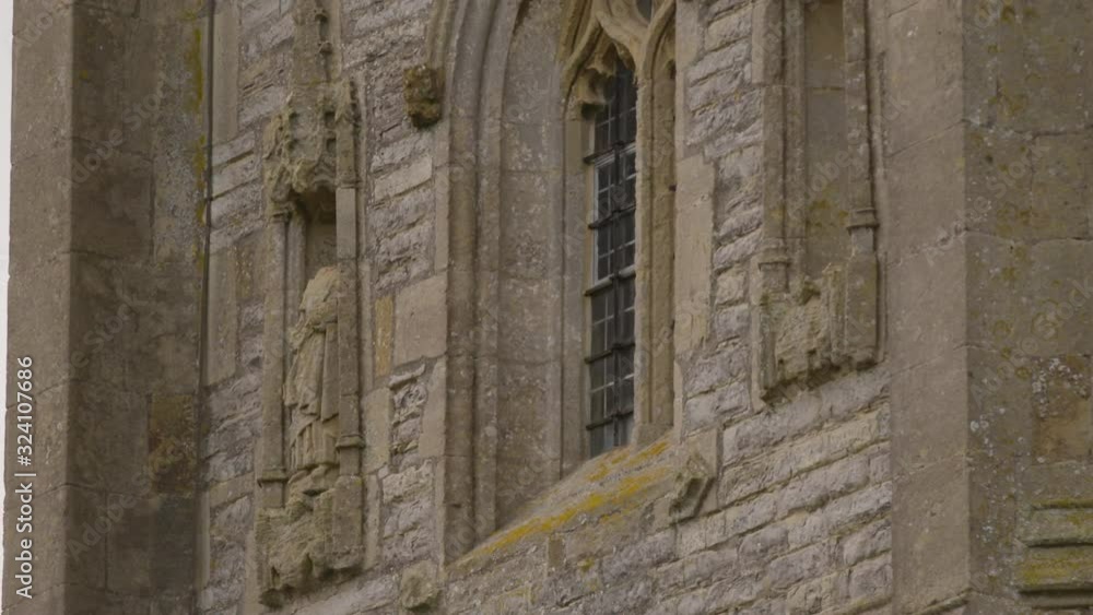 Several crows flying from their perch on a statue set in the wall of Westonzoyland church beside a window Several crows flying from their perch on a statue set in the wall of Westonzoyland church beside a window