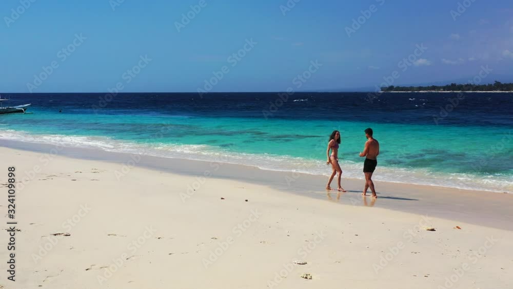 Happy young couple enjoying honeymoon vacation days on beautiful exotic beach washed by blue azure sea Happy young couple enjoying honeymoon vacation days on beautiful exotic beach washed by blue azure sea