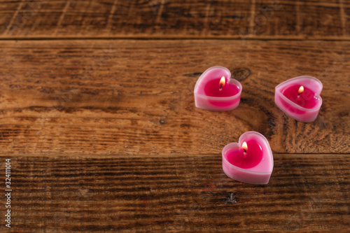 Valentine's day burning candles in the form of hearts on a wooden table. Valentine's Day celebration concept.Copy space. photo