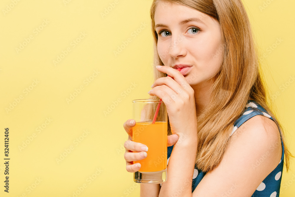 girl in dress drinking orange juice from a straw girl in dress drinking orange juice from a straw