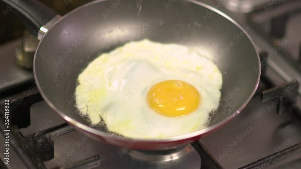 Salt and seasoning being put into an egg being fried in the pan Salt and seasoning being put into an egg being fried in the pan