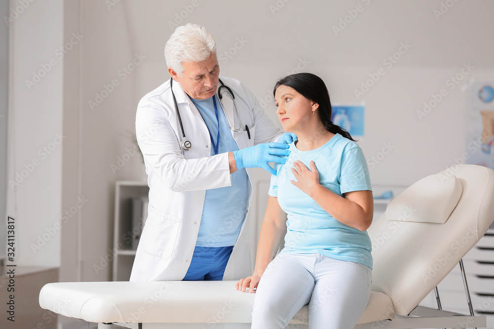 Fototapeta premium Mature male doctor working with patient in clinic