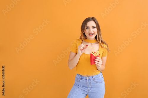 Portrait of beautiful young woman with french fries on color background
