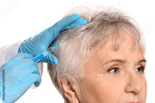 Senior woman with hair loss problem receiving injection on white background