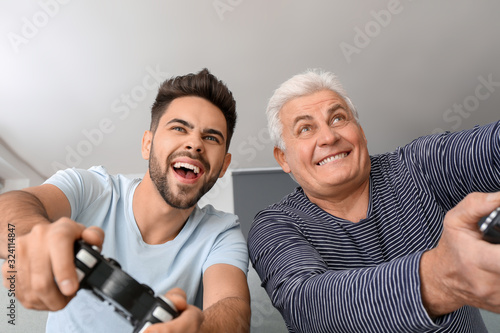 Young man and his father playing video game at home