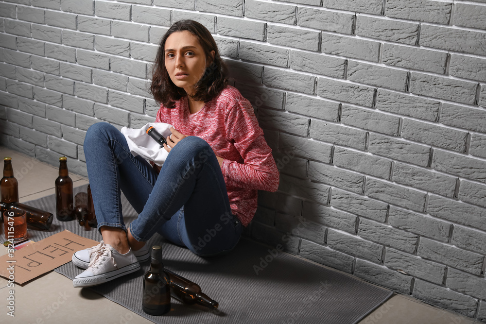 Young drunk woman near brick wall. Concept of alcoholism Young drunk woman near brick wall. Concept of alcoholism