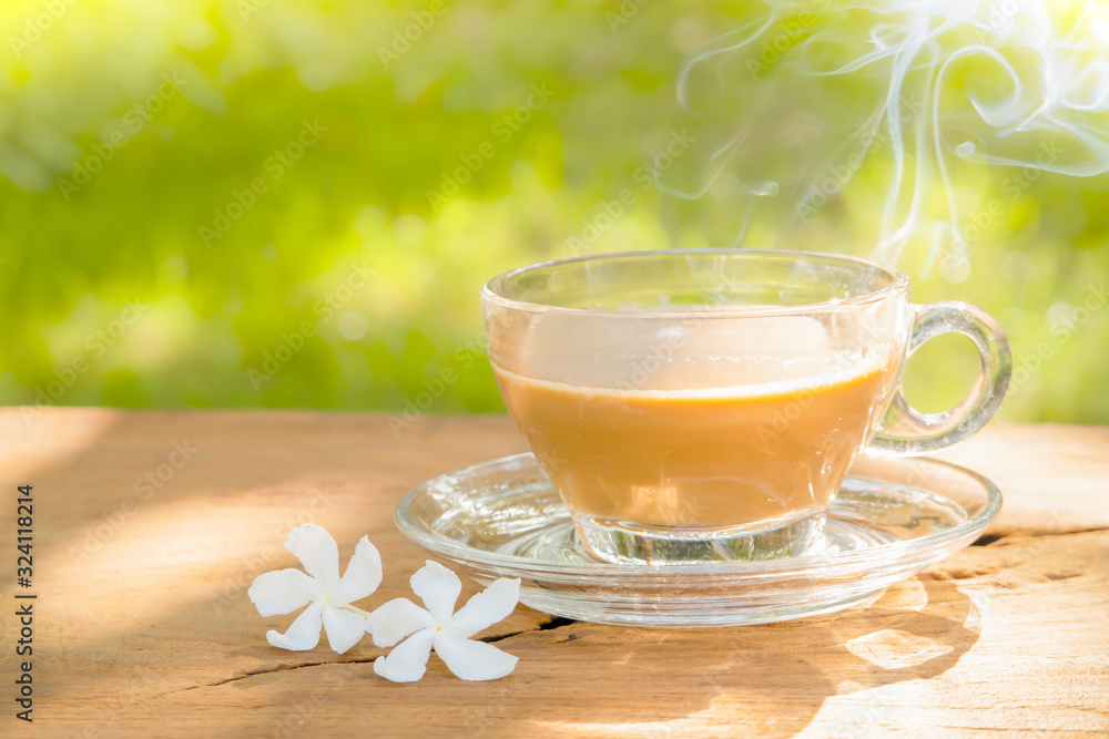 hot coffee in a coffee cup on a dark wooden table texture and natural blurred green leaf background