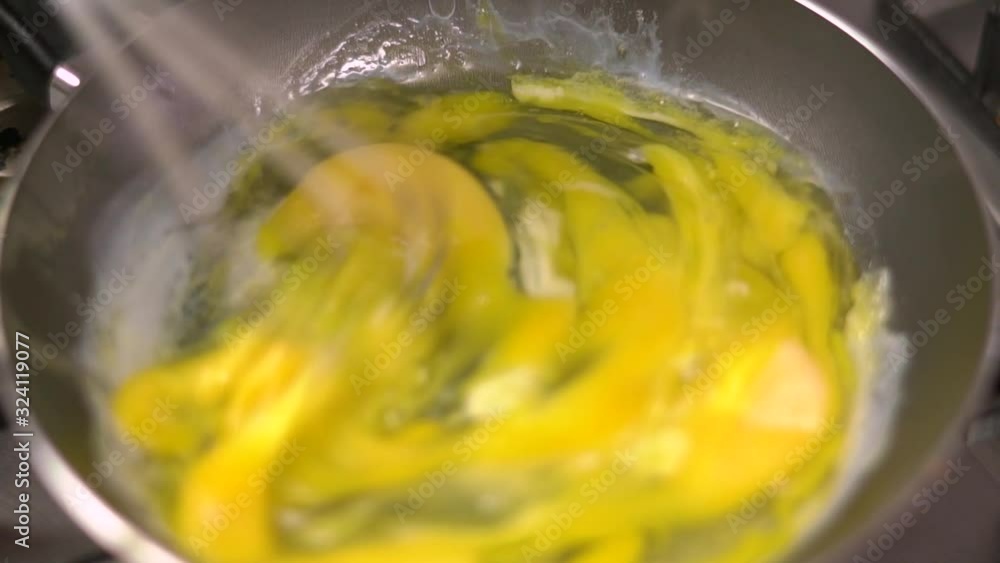 Eggs being scrambled in a frying pan by hand beater Eggs being scrambled in a frying pan by hand beater