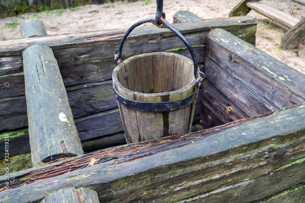 Old wooden well and a wooden bucket. The concept of rural areas and recreation in the village.