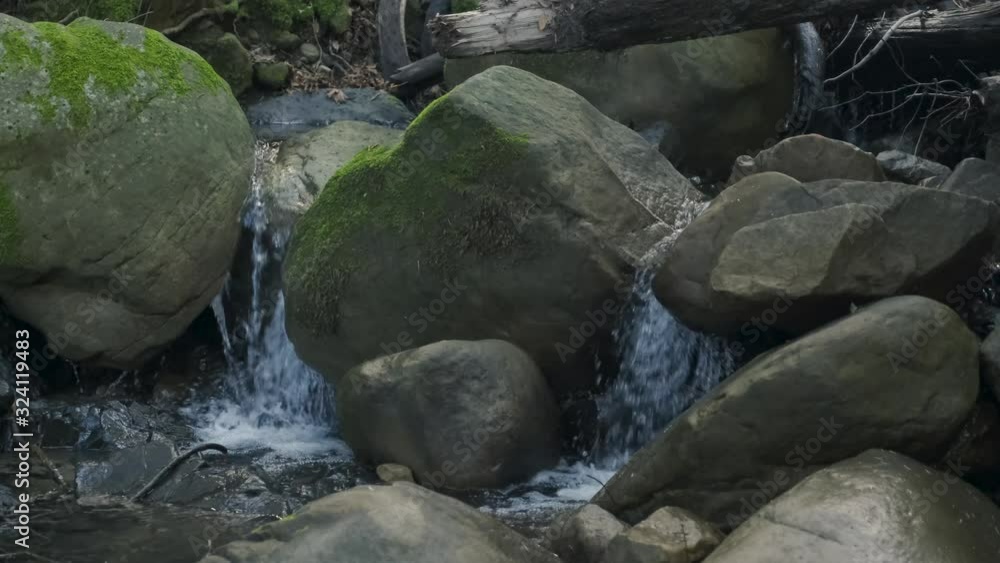 4k close up and slider of small waterfalls flowing around rocks, boulders, and into water basin, real time 4k close up and slider of small waterfalls flowing around rocks, boulders, and into water basin, real time