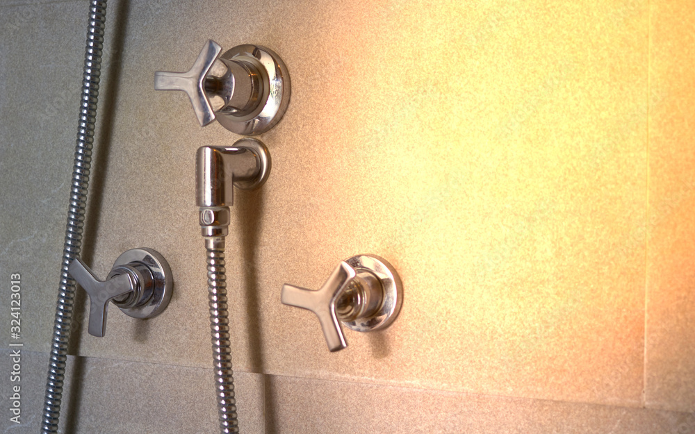 Shower tap and silver faucets on bath room wall with sun light