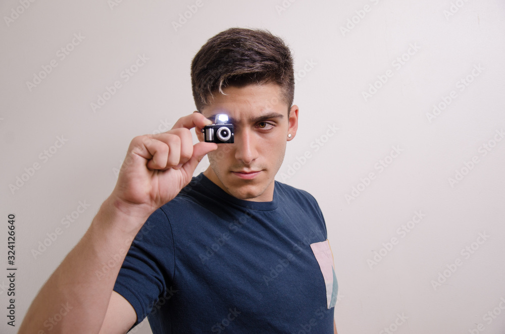 Young man with a miniature camera Young man with a miniature camera