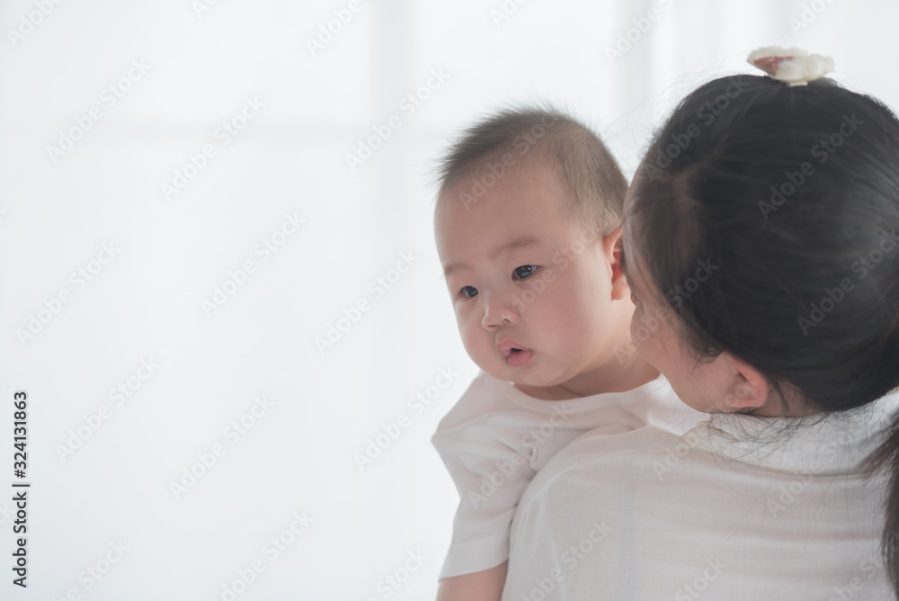 happy loving family. mother playing with her baby in the bedroom. asian mother hugging and holding her baby. family, motherhood, parenting, family and child care concept. White background. happy loving family. mother playing with her baby in the bedroom. asian mother hugging and holding her baby. family, motherhood, parenting, family and child care concept. White background.