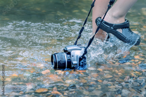 a man drags a SLR camera submerged in water on the rocky bottom of the river. concept of waterproof and reliable devices photo