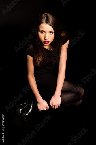 Portrait of a beautiful young woman in a black dress with a cool makeup and good skin. Studio, black background. © Oleksandr