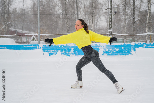 Professional skater on an outdoor ice rink. A woman on knees is preparing a solo program for the competition.