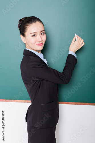 portrait of female teacher pointing to chalkboard.