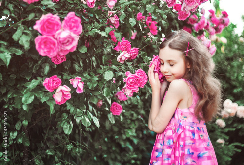 Cute little girl posing on blooming flowers background. Spring concept.