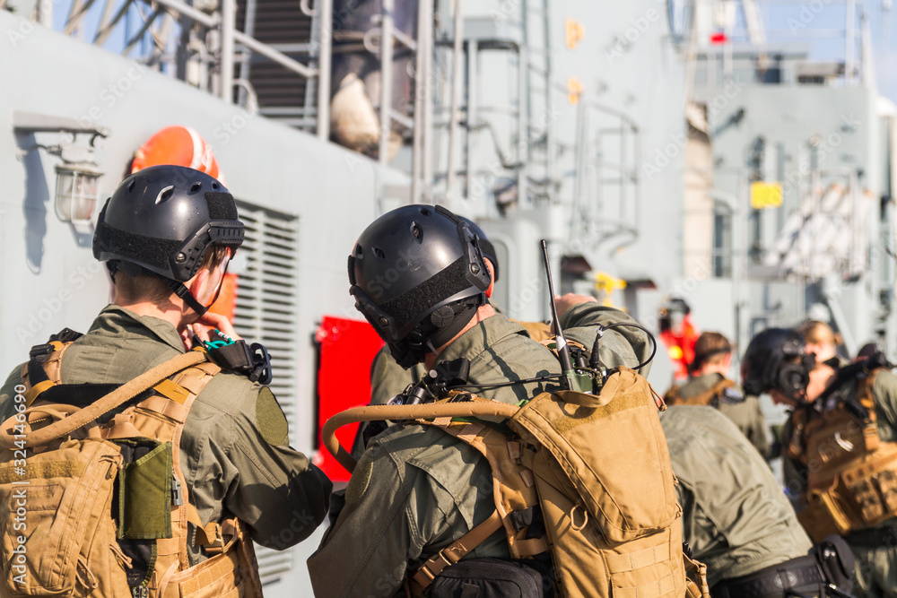 Military soldiers from special forces with weapons on ship deck,coordinate attack to enemy ship during nato exersise on sea. 