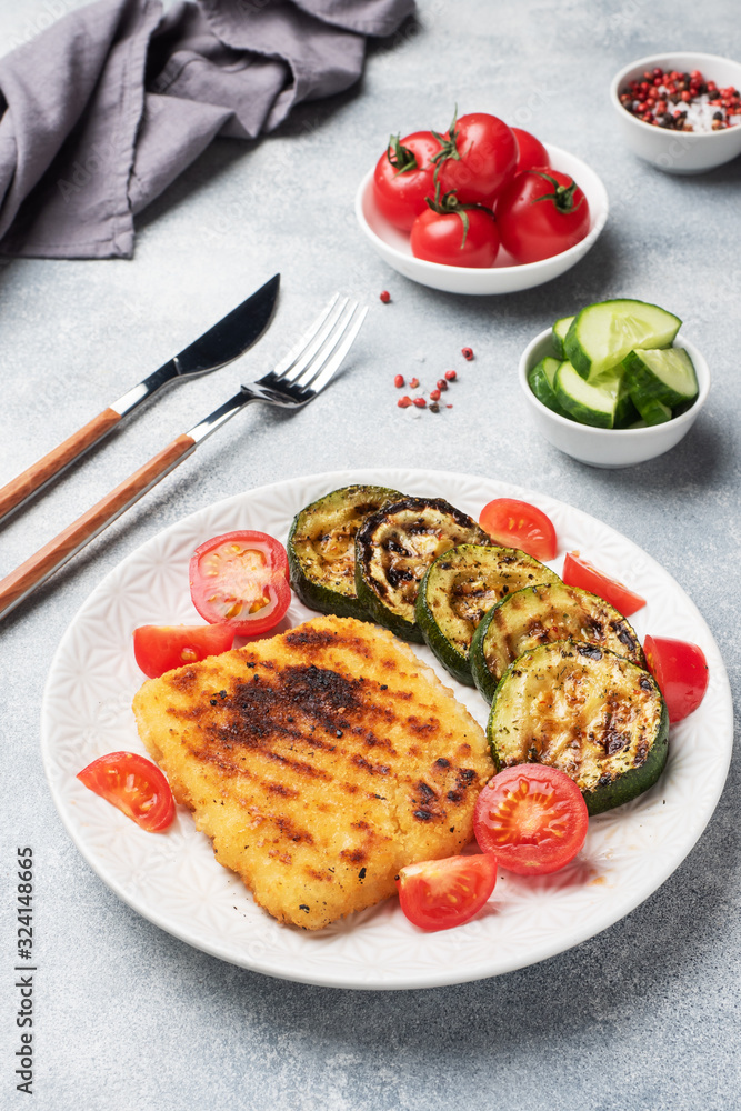 Schnitzel of chicken and zucchini cooked on the grill. Fresh tomatoes on a plate. Ready delicious dinner lunch. Schnitzel of chicken and zucchini cooked on the grill. Fresh tomatoes on a plate. Ready delicious dinner lunch.