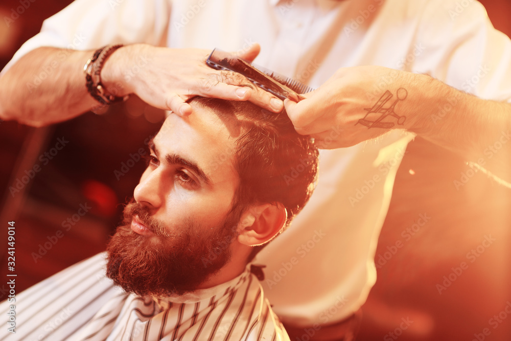 hairdresser or barber does a hairstyle to the client on the background of modern barbershop hairdresser or barber does a hairstyle to the client on the background of modern barbershop