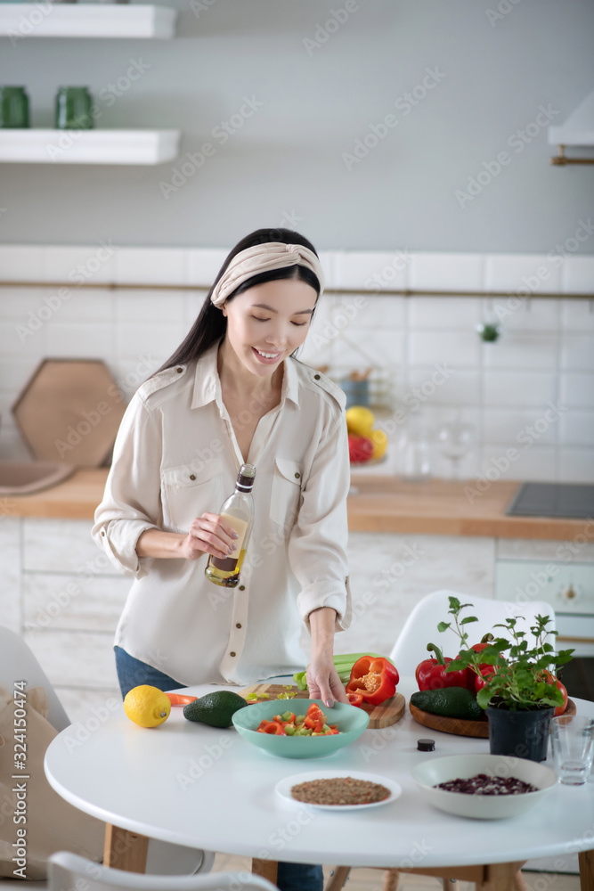 Beautiful young woman with olive oil looking at a salad. Beautiful young woman with olive oil looking at a salad.