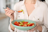 Female hands holding fork and plate with bright vegetarian salad.
